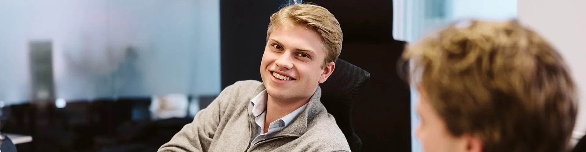 Two young men chatting in an office setting.