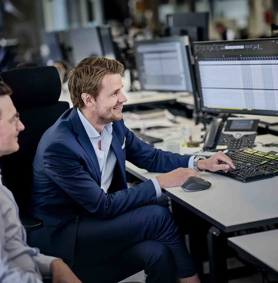 Two men working at a computer desk in an office.