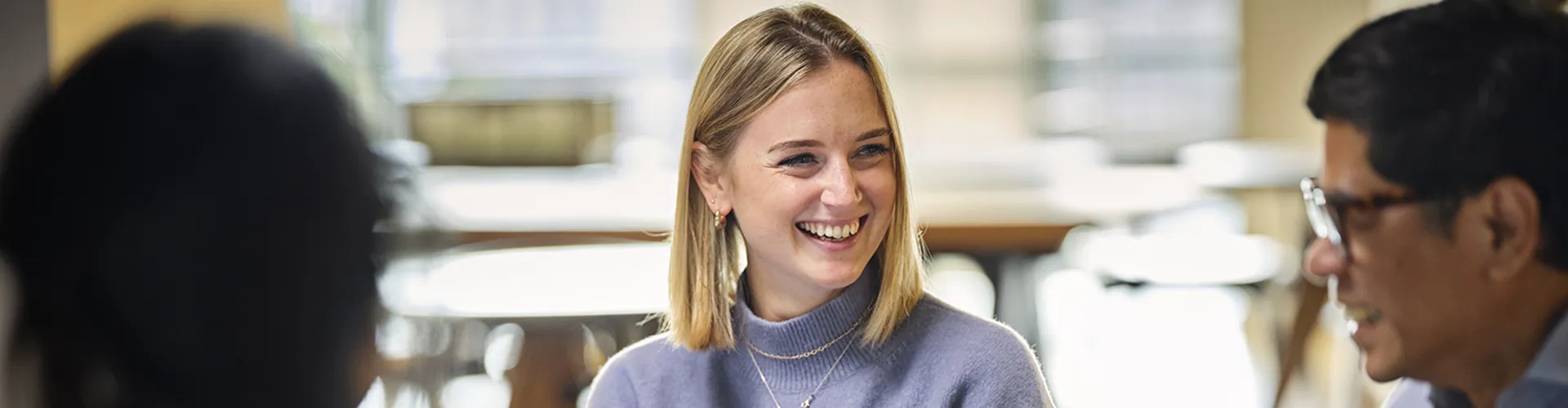 woman sitting at a table with colleagues smiling and talking