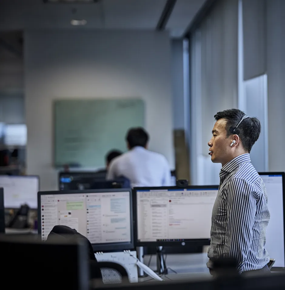 Man in a striped shirt using a headset in an office.