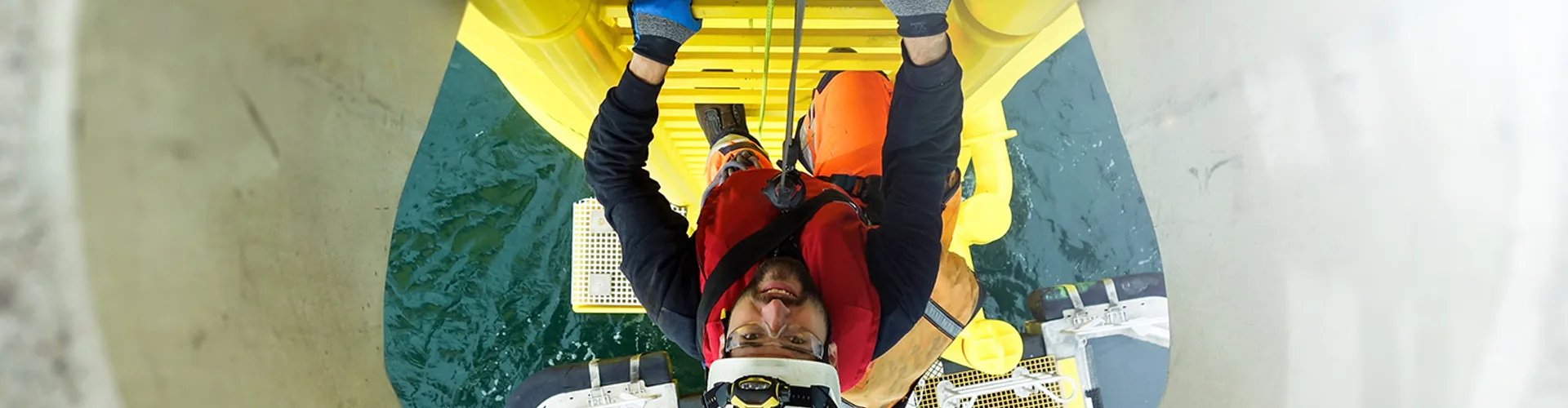 Manual high worker offshore climbing on wind-turbine on ladder and transfer vessel waiting under wind turbine