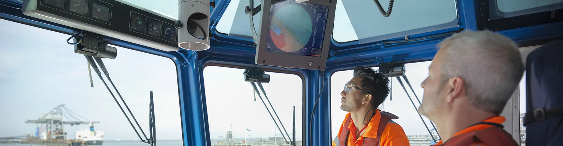 Tug workers wearing protective clothing steering tug