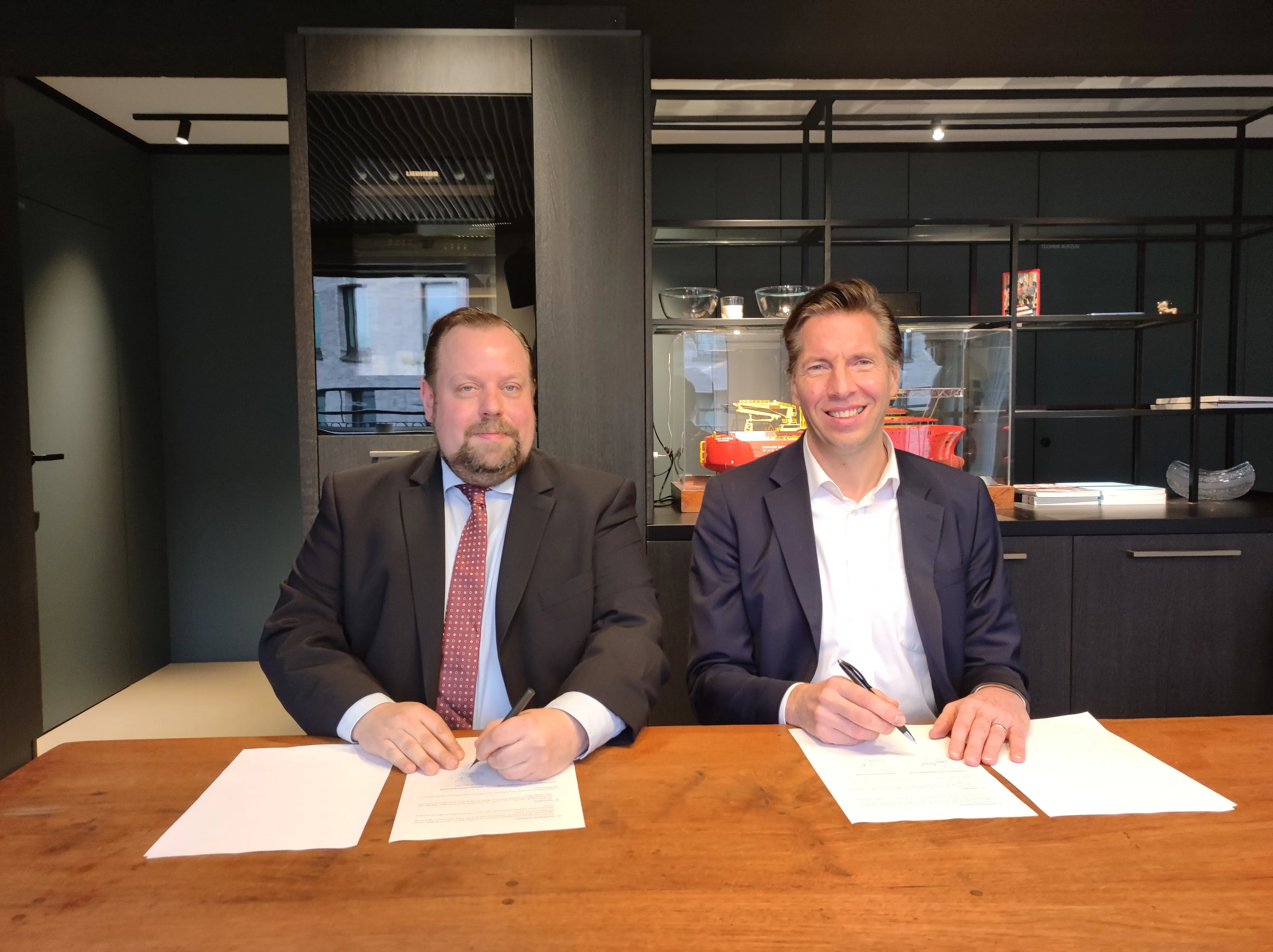 two men sitting at a table signing documents