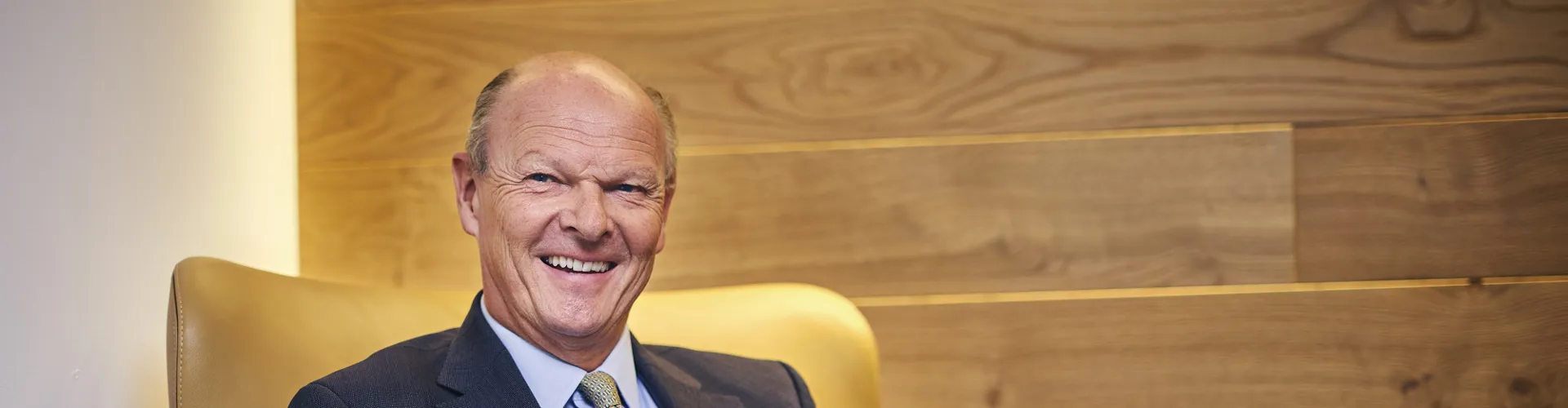 Laurence Hollingworth sitting in a chair smiling