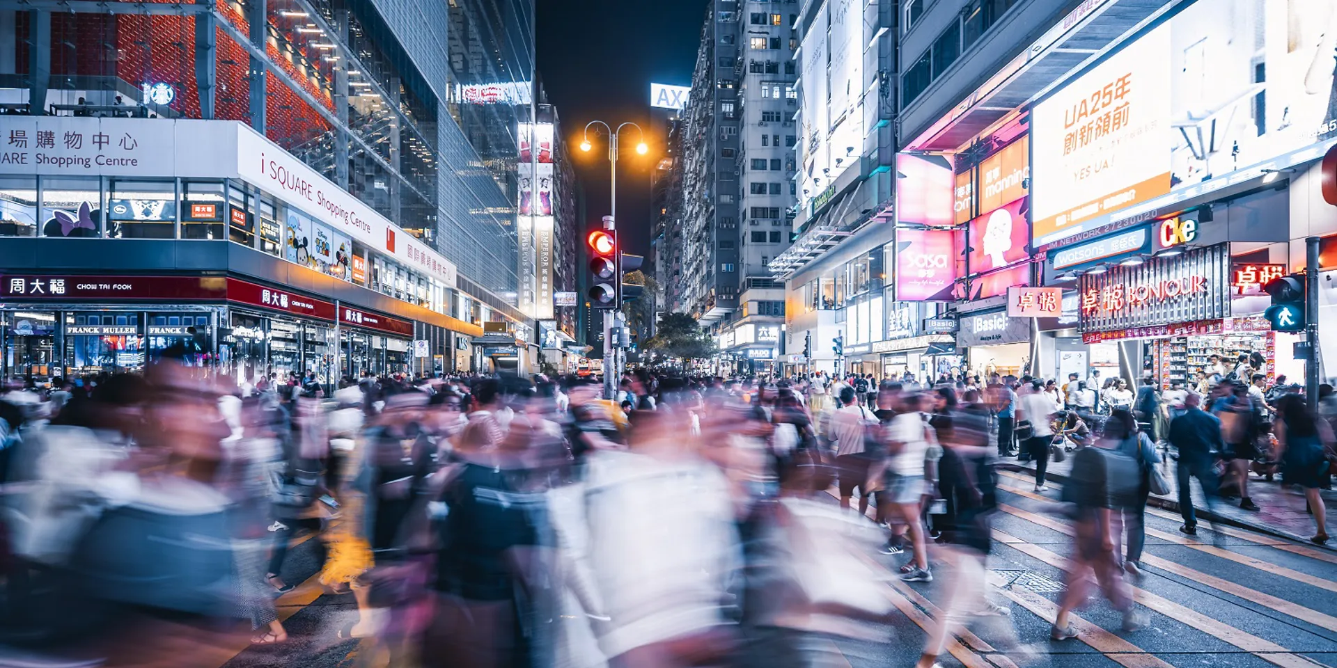 Busy street at night with blurred pedestrians.