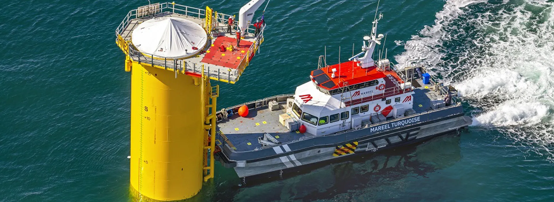 Boat near a yellow offshore platform in blue water.