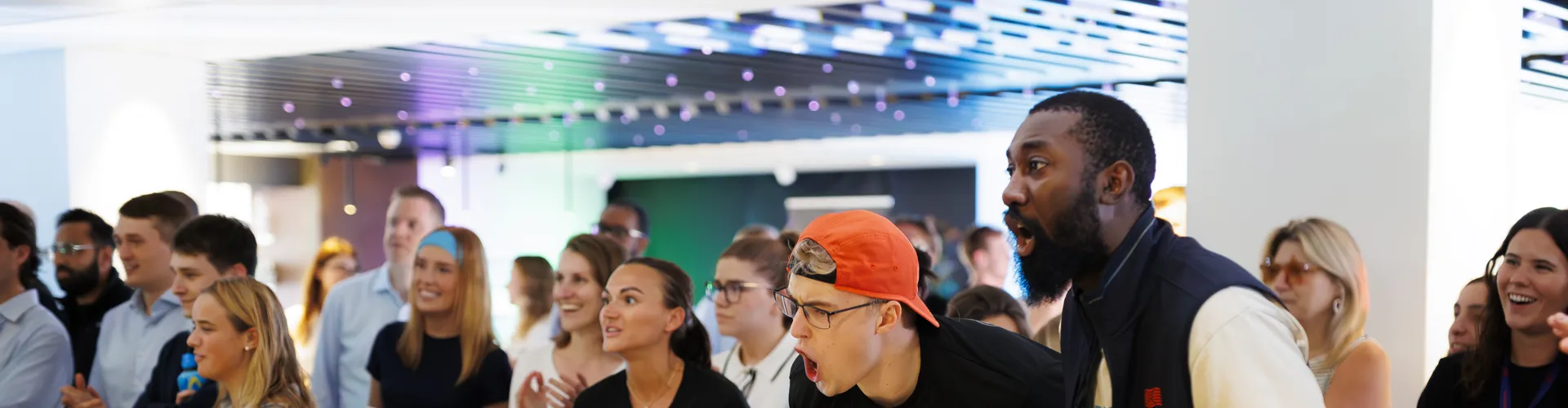 Diverse group gathered in a lively setting with expressions of excitement and engagement.