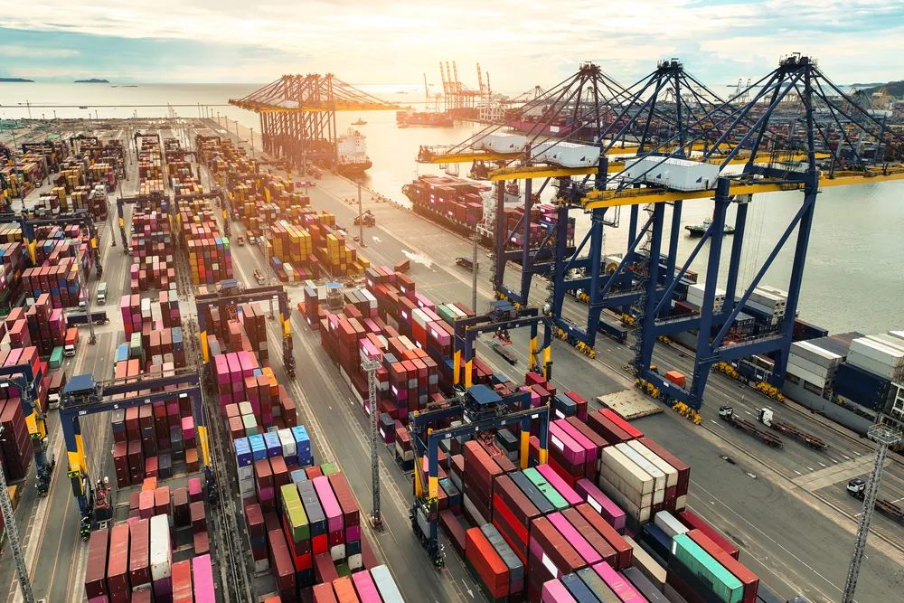 Container ship berthed at a container terminal with cargo trucks on the quayside