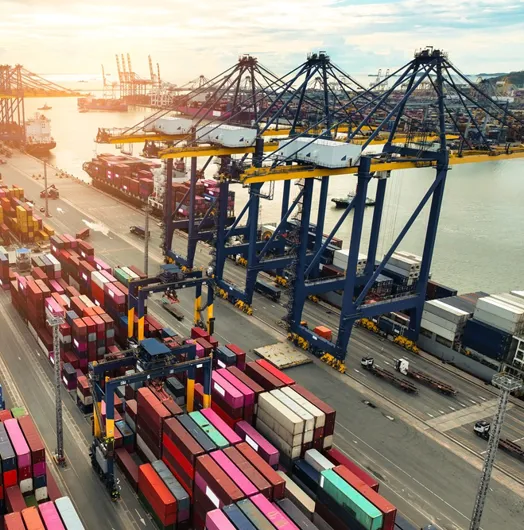 Container ship berthed at a container terminal with cargo trucks on the quayside