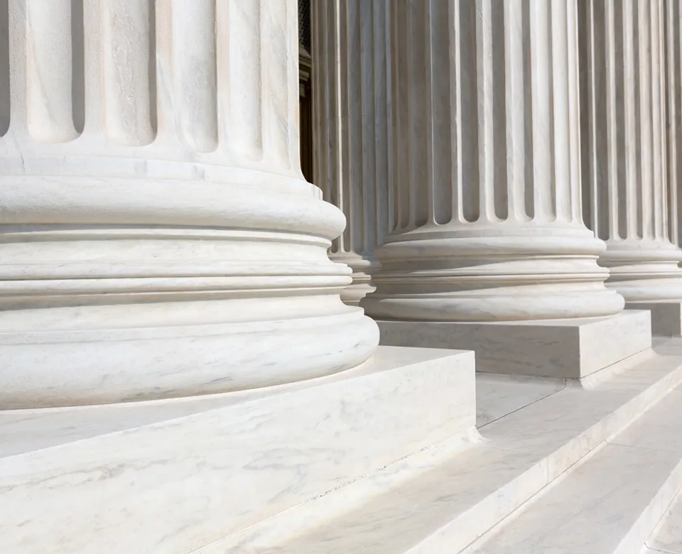Close-up of several classical white marble columns with fluted designs.