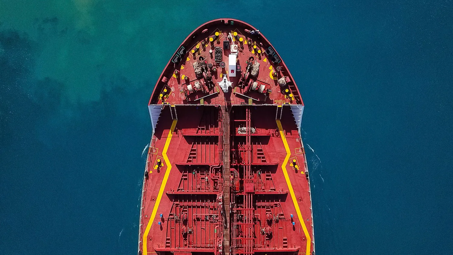 Top view of a large red cargo ship on blue water.