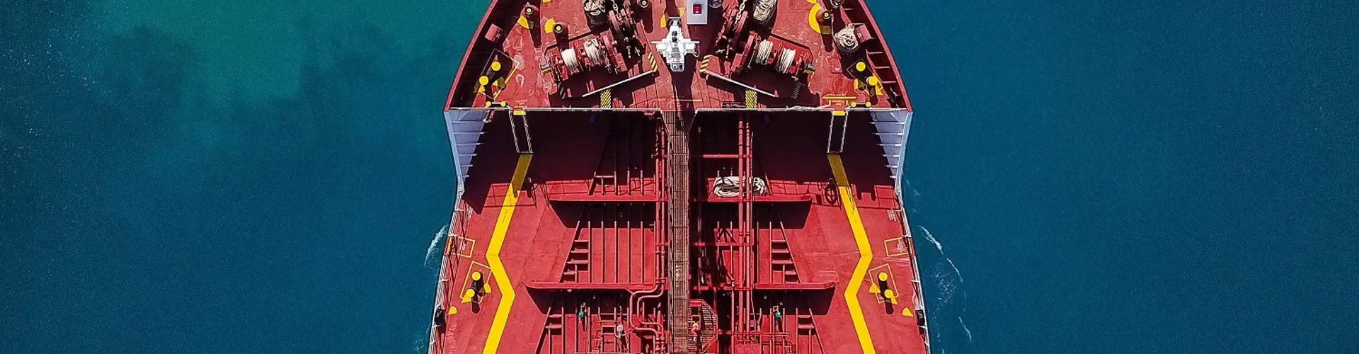 Top view of a large red cargo ship on blue water.