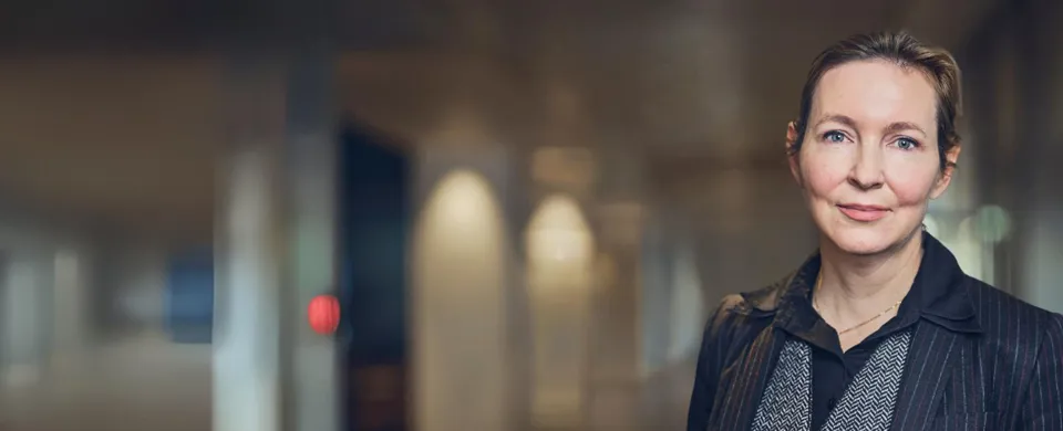 Woman in a blazer standing in a modern interior.