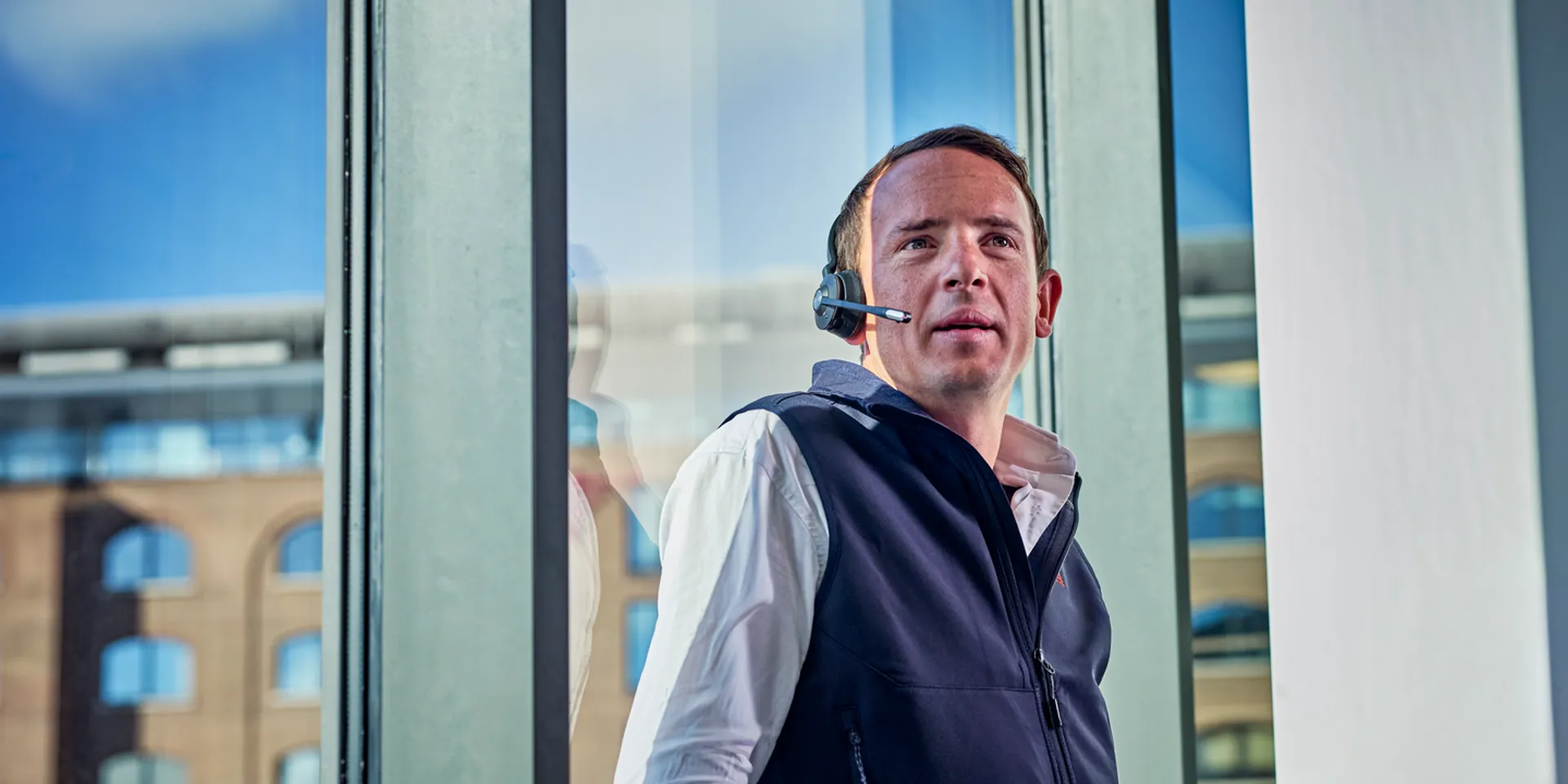 Man with headset standing by office window