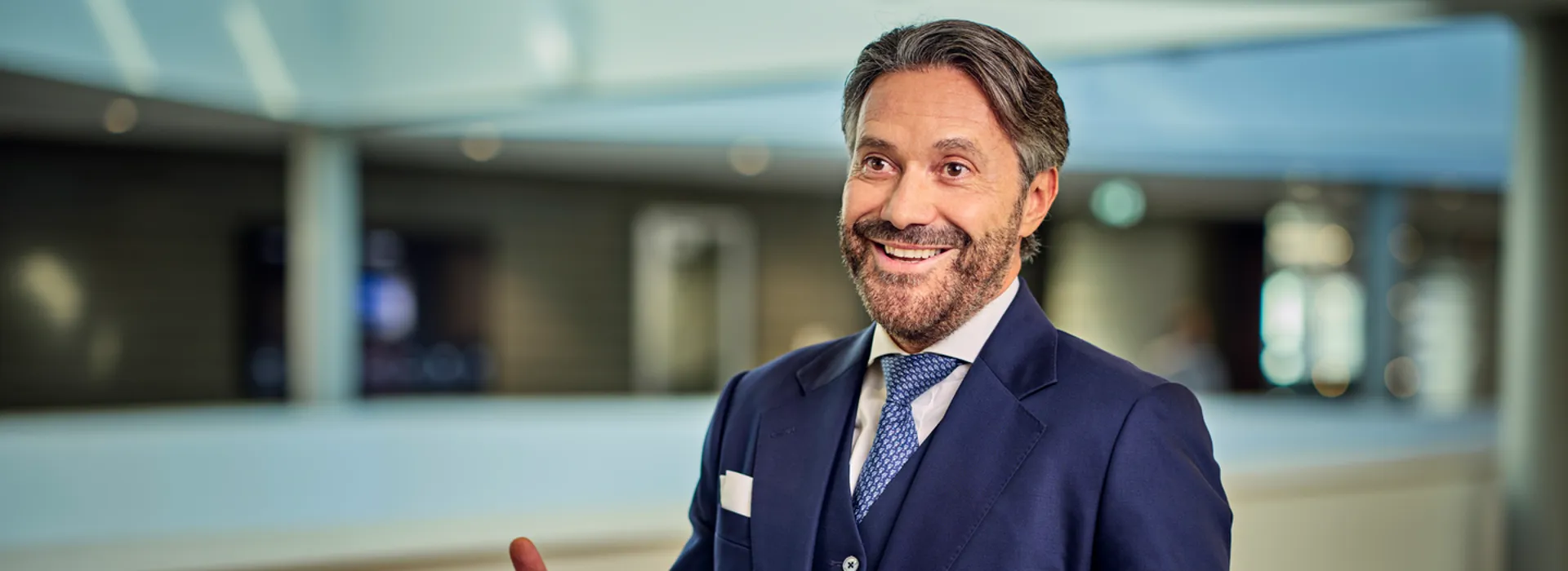 Bearded man in dark suit speaking animatedly