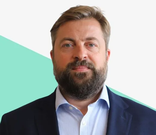 Bearded man in dark suit, teal background