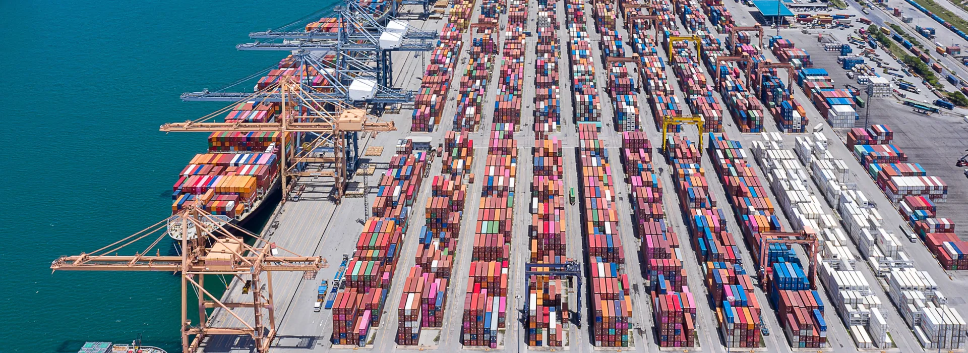 Aerial view of a container port with cranes and stacked shipping containers